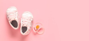 Pembe arka planda emziği olan şık bebek ayakkabıları.