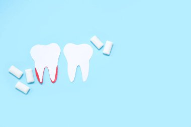 Kağıt dişler ve mavi arka planda beyaz diş etleri.