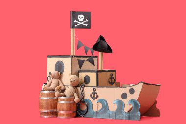 Kırmızı arka planda varilleri ve oyuncak ayıları olan korsan karton gemi.