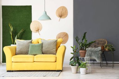 Sarı kanepeli ve çiçekli aydınlık oturma odasının içi.