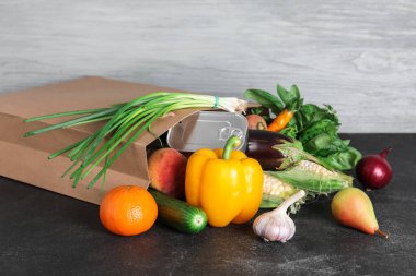 Siyah masanın üzerinde farklı ürünler olan kağıt torba.