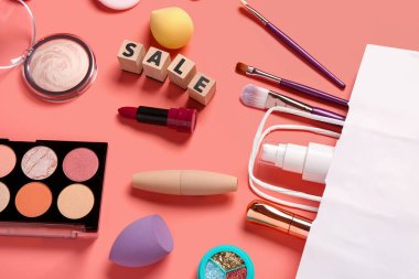 Makyaj malzemeli alışveriş çantası ve pembe arka planda metin satışı