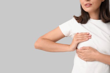 Genç bir kadın göğsünü arka planda kontrol ediyor, yakın plan. Kanser farkındalığı kavramı