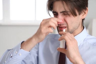 Hasta işadamı ofiste burun damlası kullanıyor, yakın plan.