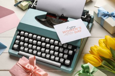 Kadınlar Günü için daktilo, laleler ve beyaz ahşap masada hediye kutusu üzerinde şenlikli kartpostal.