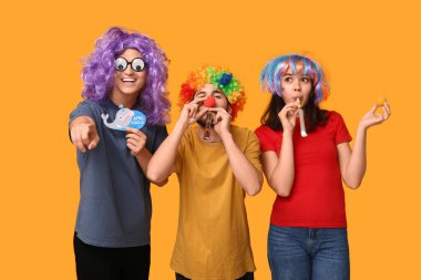 Sarı arka planda ıslık çalan komik görünümlü genç arkadaşlar. 1 Nisan kutlamaları