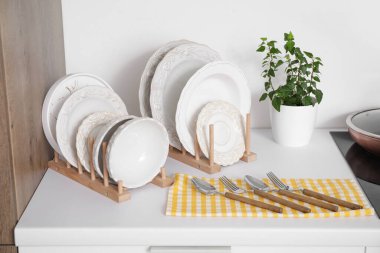 Mutfaktaki beyaz tezgahın yanında farklı temiz bulaşık takımları var.