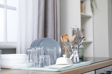 Mutfakta temiz bardaklar, çatal bıçak takımı ve tabaklar var.