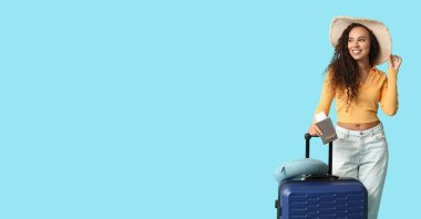 Çantası, pasaportu ve açık mavi arka planda bileti olan genç bir Afro-Amerikalı kadın. Mesaj için yeri var. Seyahat kavramı