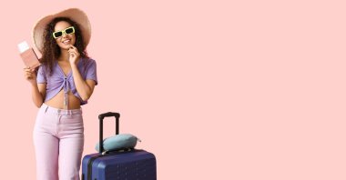 Çantası, pasaportu ve pembe arka planda bileti olan genç bir Afro-Amerikalı kadın. Mesaj için yeri var. Seyahat kavramı