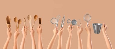 Birçok el bej arka planda pişirme aletleri tutuyor