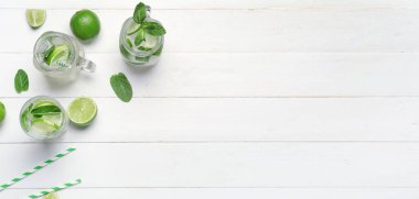 Mason kavanozları ve beyaz ahşap zemin üzerinde lezzetli mojito bardakları metin ve üst görünüm için yer var.