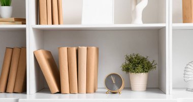 Kitapları, saati ve dekorasyonu olan raflar.