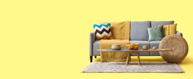 Rahat gri kanepe, masa ve hasır puf ile sarı arkaplan metin için yer ile