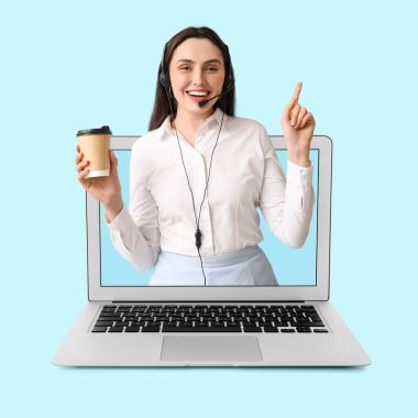 Açık mavi arka planda dizüstü bilgisayarından kahve fırlatan kadın teknik destek ajanı