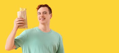 Sarı arkaplanlı lezzetli sandviçli mutlu genç adam mesaj için yeri var.