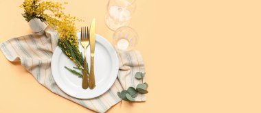 Mimoza çiçekleri ve okaliptüs ile açık sarı arkaplan üzerinde güzel masa ayarları ve metin için boşluk