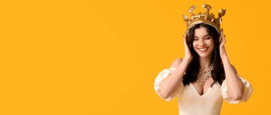 Şık bir balo elbisesi ve sarı arka planda taçlı, mesaj için yeri olan güzel bir genç kız.