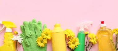 Temizlik malzemeleri ve bahar çiçekleri pembe arka planda, üst manzara