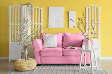 Kanepesi, masası, katlanır perdesi ve çiçek açan dalları olan güzel bir oturma odası.