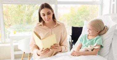 Annesi klinikte kitap okurken kemoterapiden sonra küçük bir kız.