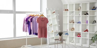 Elbiseli askı, raflarda ayakkabılar ve hafif soyunma odasında ayna.