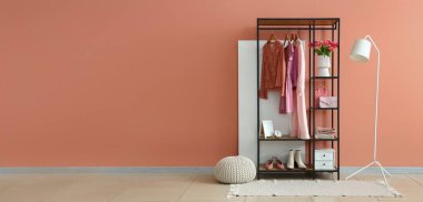 Pembe duvarın yanında giysi ve aksesuarlı şık bir oda. Tasarım için pankart