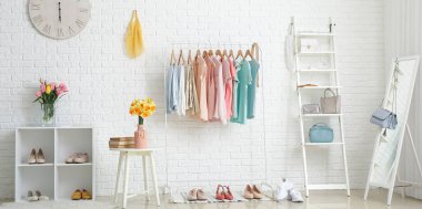 Bahar giysileri, aksesuarları ve aynalarıyla aydınlık soyunma odasının içinde.