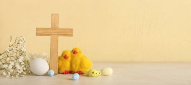 Ahşap haç, civcivler, renkli arka planda boyanmış yumurta ve çiçekler ve metin için yer. Paskalya kutlaması
