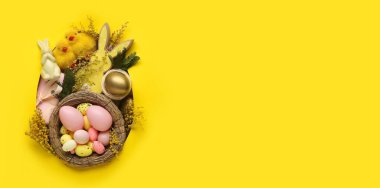 Sarı zemin üzerinde paskalya yumurtaları ve çiçekler metin ve üst görünüm için yer var.
