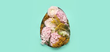 Turkuaz arka plandaki yumurta şeklindeki delikten görülebilen farklı çiçekler. Paskalya kutlaması