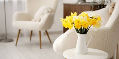 Oturma odasının içinde nergis çiçekleri olan küçük bir masa.