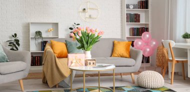 Uluslararası Kadınlar Günü hediyesi olarak, içinde kanepe, vazo ve laleler olan oturma odasının içinde.