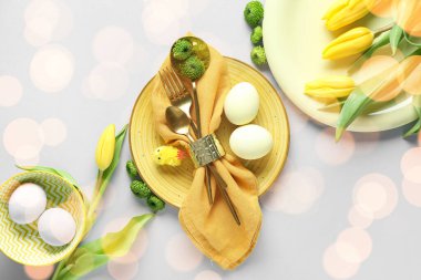 Paskalya kutlaması için hafif arka planda çiçekler ve yumurtalarla şık bir masa.