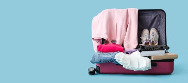 Klasik daktilo ve seyahat aksesuarlarıyla birlikte açık mavi arkaplan ve metin için boşluk olan bavulu aç