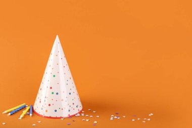 Parti şapkası, doğum günü mumları ve renkli arka planda konfeti