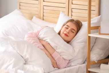Yumuşak yastıklı genç kadın yatakta uyuyor.