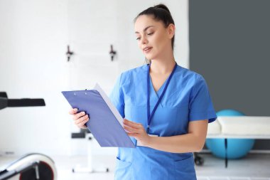 Rehabilitasyon merkezinde panosu olan kadın fizyoterapist.