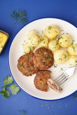 Pirzola tabağı, haşlanmış bebek patatesler ve mavi arka planda dereotu.