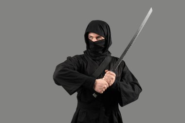 Gri arka planda kılıcı olan erkek ninja.