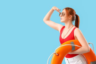 Mavi arka planda halka şamandırası olan kadın cankurtaran.