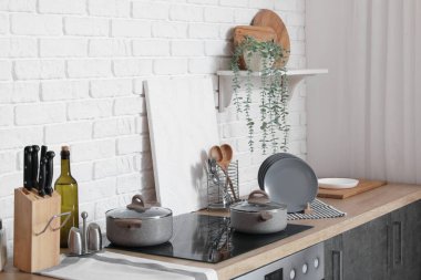 Tabak askılı ahşap tezgah, kesme tahtası, mutfak aletleri ve elektrikli soba.