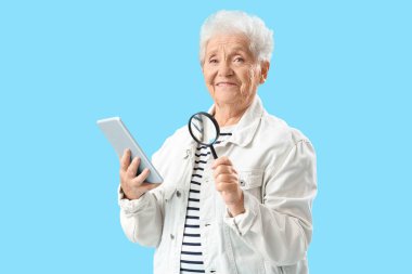 Mavi arka planda büyüteç ve tablet bilgisayarı olan yaşlı bir kadın.