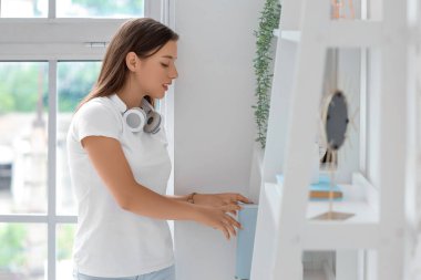 İzin gününde kitaplarını raftan alan genç bir kadın.