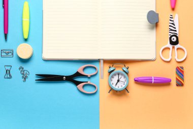 Renkli arkaplanda farklı kırtasiye malzemesi olan defter