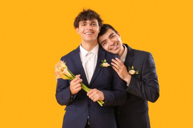 Sarı arka planda çiçekleri olan evli eşcinsel çift.