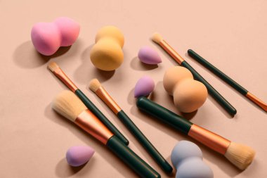 Bej arka planda makyaj süngerleri ve fırçalar