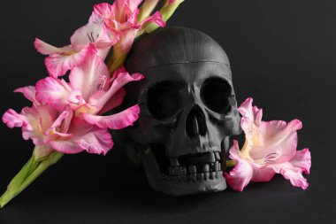 Siyah arka planda güzel zambak çiçekleri olan insan kafatası