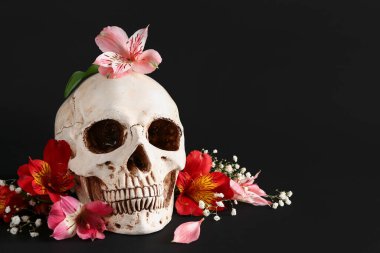 Siyah arka planda güzel zambak ve çigila çiçekleri olan insan kafatası