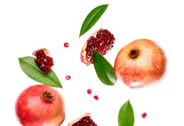 Tohumları ve yaprakları beyaz arkaplanda uçuşan taze narlar.